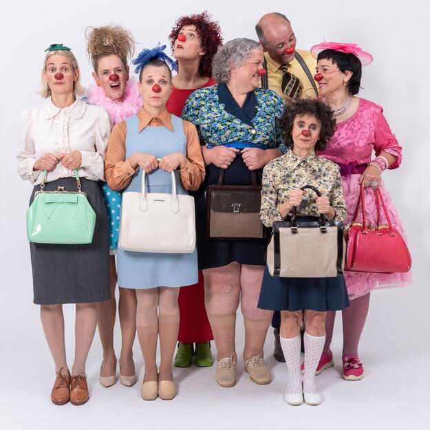 Una foto di gruppo con un clown e diverse clown con il naso rosso e abiti colorati.